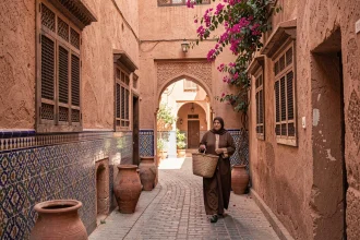Ruelle typique de la médina de Marrakech avec murs en pisé ocre, céramiques artisanales et bougainvillées, illustrant le charme immobilier du centre historique