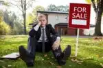 agent immobilier devant une maison à vendre