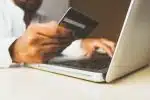 person using laptop computer holding card